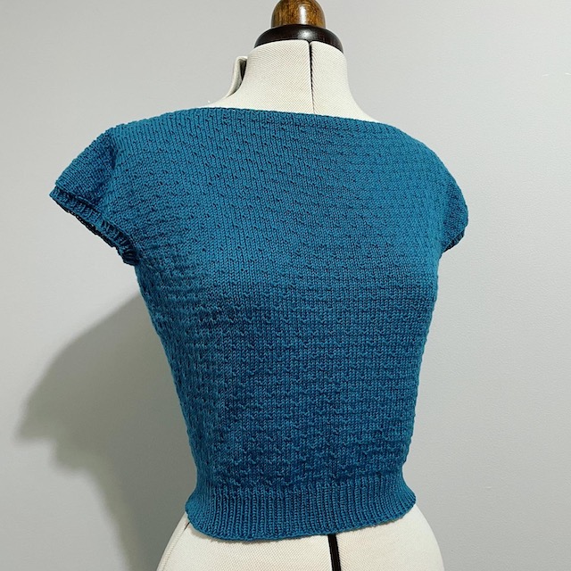 A hand-knitted top with a 50's aesthetic in a glorious deep turquoise shade.